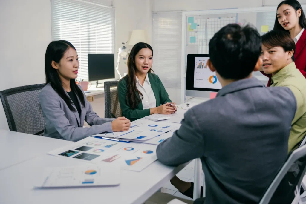 Asian business team discussing financial charts in office meeting